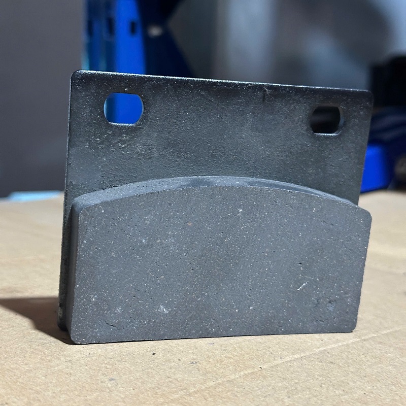 Cấu tạo chi tiết má phanh xúc lật – gồm đế kim loại và lớp ma sát chuyên dụng